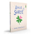 Livro Amor & Sorte de Jenna Evans Welch, capa bege com trevo de quatro folhas rosa e verde. — Plenitude